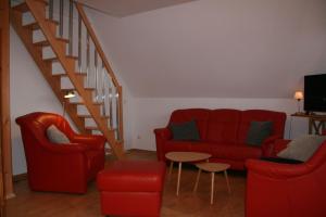 a living room with red furniture and a staircase at Nickelshus-Whg-Veit in Sankt Peter-Ording