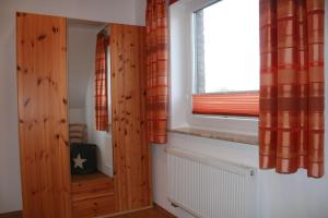 a room with a window with orange curtains and a radiator at Nickelshus-Whg-Veit in Sankt Peter-Ording