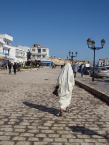a woman walking down a street with a white coat at Dar Warda in Bizerte