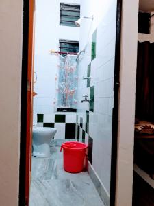 a bathroom with a toilet and a red bucket at D.D Lodge in Guwahati