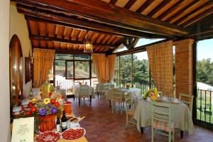 un comedor con mesas, sillas y ventanas en Hotel La Fonte Del Cerro en Saturnia