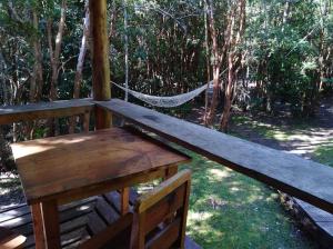 a wooden bench sitting on a porch with a hammock at Cabaña en Río Puelo in Puelo