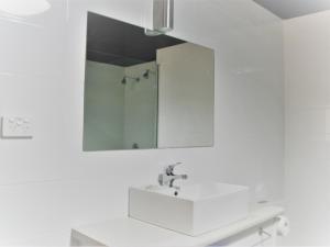 uma casa de banho branca com um lavatório e um espelho em Daydream Motel and Apartments em Broken Hill