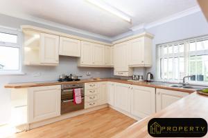 a white kitchen with white cabinets and wooden floors at Vale View in Durham