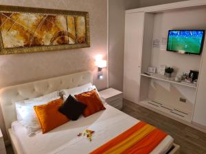 デセンツァーノ・デル・ガルダにあるB&B Gardacharmeのベッドルーム1室(オレンジ色の枕とテレビ付)