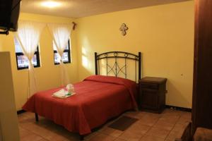 a bedroom with a bed with a red blanket and a dresser at Villas Tonantzintla in Cholula