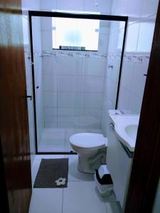 ein Bad mit einer Dusche, einem WC und einem Waschbecken in der Unterkunft Condomínio Villagio II in Caraguatatuba