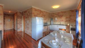 a kitchen with a white refrigerator and a wooden floor at Golfers Inn in Tenterfield