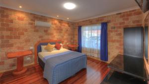 a bedroom with a bed and a brick wall at Golfers Inn in Tenterfield