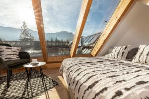 um quarto com uma grande janela com uma cama e uma cadeira em APARTHOTEL ROYAL RESORT SPA Zakopane em Zakopane
