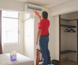 a man standing on a bed using a air conditioner at Hotel Aurora in Oaxaca City