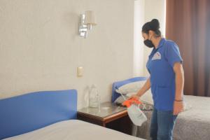 a woman in a hospital room cleaning a bed at Hotel Aurora in Oaxaca City
