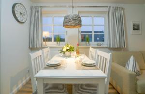 tavolo bianco con sedie e orologio da pranzo di App. Kliff a Westerland