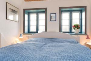 - une chambre avec un lit bleu et 2 fenêtres dans l'établissement Hansen-Hof-Wohnung-2, à Tinnum