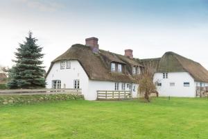 ein großes weißes Haus mit einem Strohdach in der Unterkunft Hansen Hof, Wohnung 2 in Tinnum