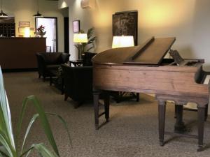 un pianoforte in legno in una stanza con sedie di The Inn at Stone Mill a Little Falls