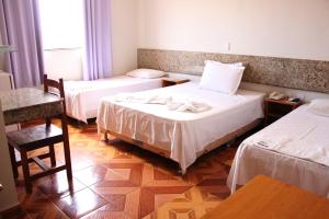 a hotel room with two beds and two chairs at Hotel Litoral in Aracaju