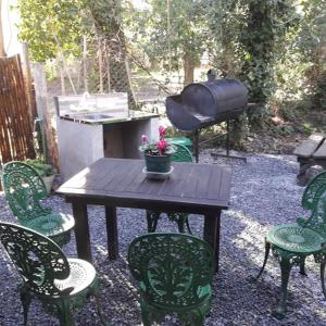 een tafel met stoelen en een grill met een bloempot erop bij Cabaña La Strega in Tandil