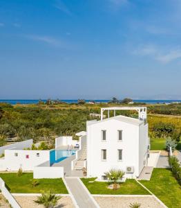 a white house with a swimming pool and the ocean at ASTERIA PEARL VILLA 2 with Rooftop Jacuzzi in Tigaki