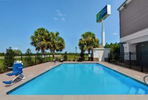 a swimming pool at a hotel with a chair next to a building at Holiday Inn Express Atmore, an IHG Hotel in Atmore