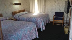 a hotel room with two beds and a chair at Sunset Inn in Lee