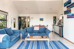 a living room with blue couches and a table at CrossTrees Chalet - Seaview - Waiheke Holiday Unit in Te Whau Bay