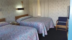 una habitación de hotel con 2 camas y una silla en Sunset Inn, en Lee