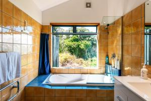 Te Whau BayにあるCrossTrees Chalet - Seaview - Waiheke Holiday Unitのバスルーム(バスタブ付)、窓が備わります。
