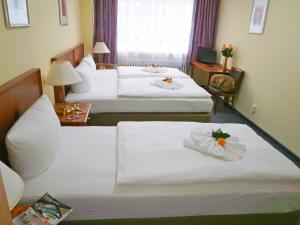 una habitación de hotel con 2 camas con flores. en Hotel Amadeus Central, en Berlín