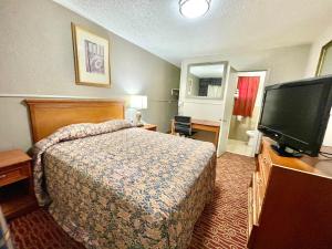 a hotel room with a bed and a flat screen tv at Magnolia Motel Donaldsonville in Donaldsonville