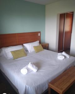 a large white bed with two towels on it at excelente departamento 4 personas villa Dina huapi 2 ambientes amplios PB in Dina Huapi