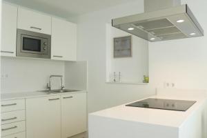 a white kitchen with a sink and a microwave at Trisara - Las Playitas in Las Playas