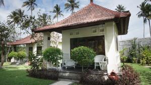 a small house with a lawn and palm trees at Puri Rinjani Bungalows in Kuta Lombok
