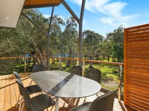 a patio with a table and chairs on a deck at The Wharf House at Budgewoi in Budgewoi