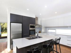 a kitchen with black and white cabinets and a counter at The Wharf House at Budgewoi in Budgewoi