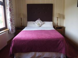 a bedroom with a large bed with a purple blanket at O'Sheas Ceol Na Habhann B&B in Kenmare