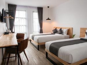 北碧Ananzitra Hotel的一间有两张床、一张桌子和一张书桌的酒店房间