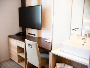 a bathroom with a desk with a tv and a sink at Kawagoe Tobu Hotel in Kawagoe