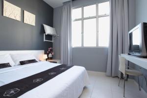 1 dormitorio con 1 cama y escritorio con TV en Wan Loong Hotel, en Pontian Kecil