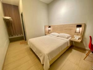 1 dormitorio con cama blanca y cabecero de madera en Wan Loong Hotel, en Pontian Kecil