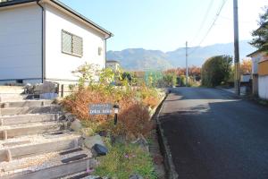 une maison avec un panneau sur le côté d'une route dans l'établissement Yamanobenomichi teku teku, à Tenri