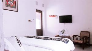 a white bedroom with a bed and a tv at nDalem Joglo Krawitan Syariah in Yogyakarta