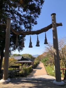 une arche en bois avec des cloches suspendues au-dessus d'un chemin de terre dans l'établissement Yamanobenomichi teku teku, à Tenri