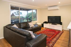 a living room with a leather couch and a flat screen tv at Eagle Bay Beach House in Dunsborough