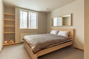 a bedroom with a large bed and a mirror at Kitsune House - walking distance to Rusutsu Resort in Rusutsu