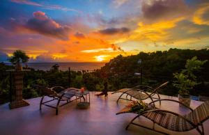 a sunset on a balcony with chairs and a table at Royal PALAZZO Italian Apartments in Boracay