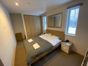 Tanuki House - walking distance to Rusutsu Resort في روسوتسو: غرفة نوم بسرير كبير ومرآة