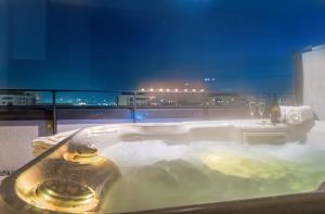 a bath tub filled with water with a view of a city at MK Apartments Brasov in Braşov
