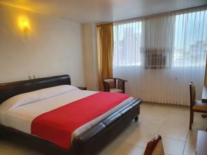 um quarto com uma cama com um cobertor vermelho e branco em Hotel Cristal em Poza Rica de Hidalgo