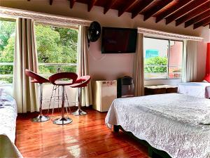 a bedroom with a bed and a table and two windows at Hotel Lleras Premium #1 in Medellín